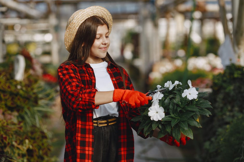 Smiling girl in plaid shirt gardening indoors with white flowers.